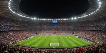 Packed stadium under floodlights during a 2025 Champions League night match, showcasing the grandeur of European football.