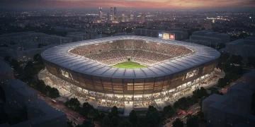 Modern European football stadium expansion with city skyline at dusk