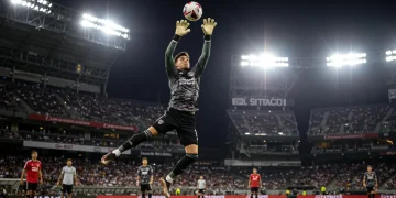 Dynamic MLS goalkeeper making a crucial save during a match, intense action