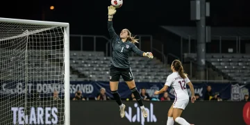 NWSL goalkeeper making a spectacular diving save during a night game.