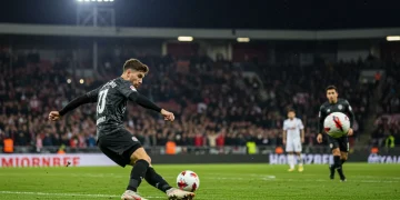 Dynamic shot of a soccer player executing a powerful free-kick, ball in flight towards goal