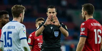 Referee signaling for a VAR check during a tense soccer match.