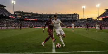 Dynamic MLS match action with a player in mid-kick, stadium lights, and an energetic crowd