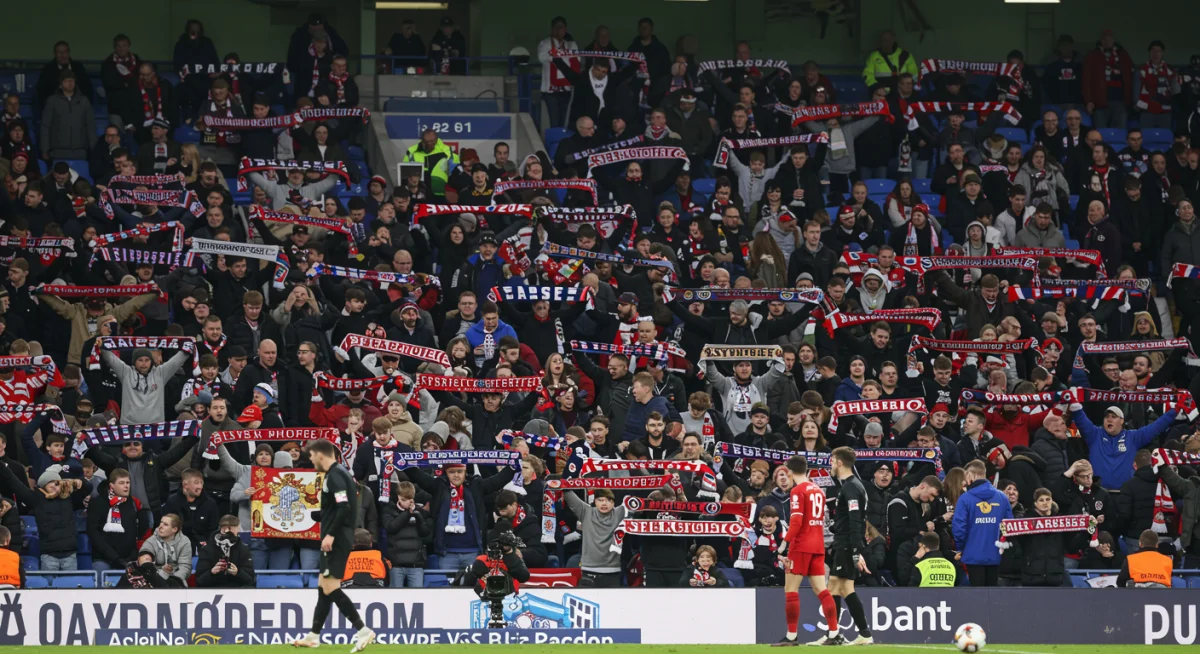 Disappointed football fans reacting to a controversial VAR call in a packed stadium.